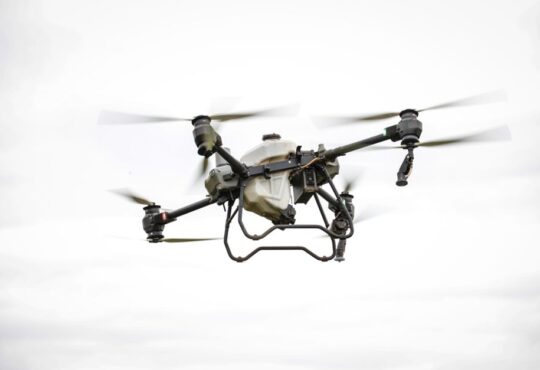 A drone capturing high-resolution aerial data for land surveying and mapping in a commercial setting.